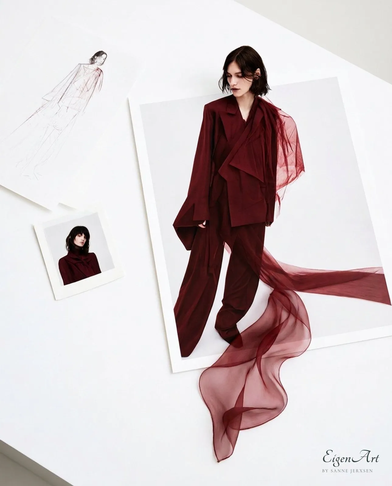 Moodboard mit feiner Skizze, Polaroid und Kampagnenabzug einer Frau im weiten bordeauxroten Anzug mit transparenter Organzabahn, die weit aus dem Foto heraus über den weißen Tisch fließt